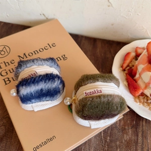 Close-up of plush macaron-shaped earphone pouches with pearl pendants and metal zippers