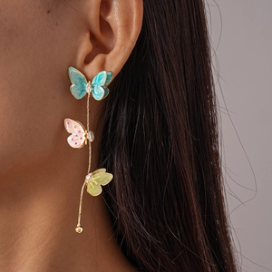 Détail de boucles d'oreilles pampilles avec papillons en émail coloré et zircons sur modèle