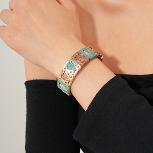 Detail of vintage elastic bracelet with bronze engraved square charms on female wrist