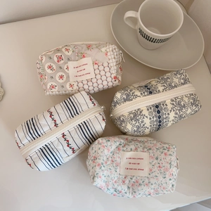 Quilted cotton floral cosmetic pouches in four patterns on a minimalist cream desk