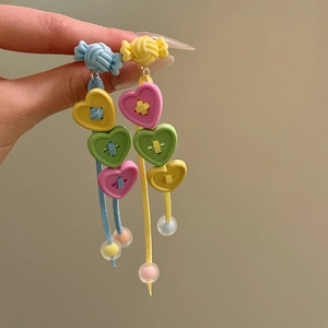 Close-up of colorful candy-shaped heart button tassel earrings with resin beads