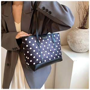 Chic black and white polka dot tote bag with gold metal plaque and black leather trim