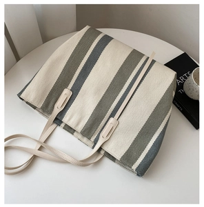 Close-up of a striped canvas tote bag on a table with a teacup and a book