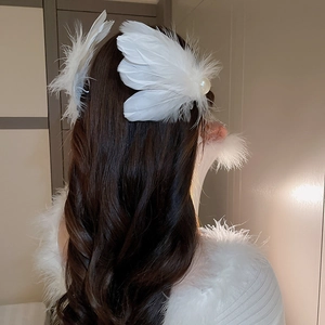 Elegant white feather hair clip with pearl detail worn on long wavy hair back view