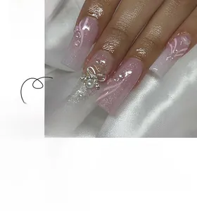 Pink gradient coffin nails with silver bows, pearls, and glitter on silk background