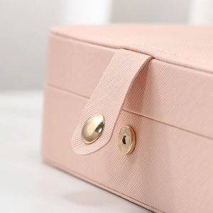 Pink faux leather jewelry box with metal snap button closure and textured finish
