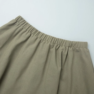 Detail of elastic waistband on olive green linen skirt showing soft pleated fabric