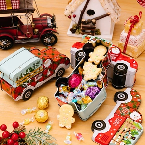 Christmas car-shaped tin candy boxes with Santa Claus and tree patterns on a wooden desk