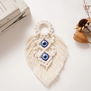 Close-up of handmade bohemian leaf wall hanging with blue evil eye beads and cotton rope