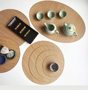 Detailed top view of natural bamboo woven tea mats in oval and round shapes with teaware