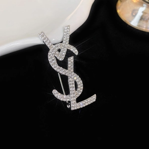 Macro shot of silver YSL logo brooch with sparkling crystal rhinestones inlay