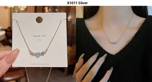 Detail of silver bow pendant necklace with light blue bead and zircon on Asian model