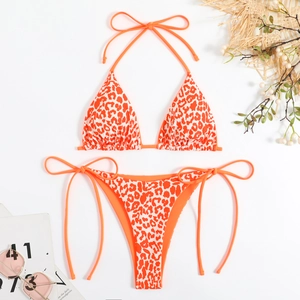 Flat lay of orange leopard print two-piece bikini with halter neck ties and beach accessories