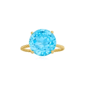 Macro detail of round light blue gemstone ring with gold twist band and four-prong setting
