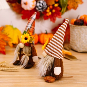 Detail of harvest gnomes with plaid hats, sunflowers and maple leaves on wooden desk
