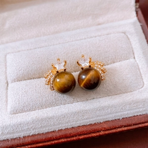 Macro shot of 18K gold-plated star earrings with tiger eye stone and crystals