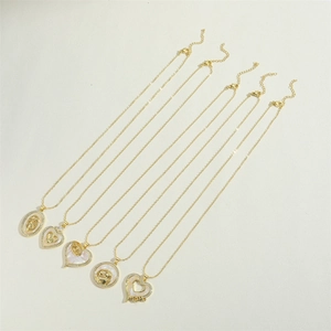 Detail of five gold MOM pendant necklaces with heart and shell inlay on beige background