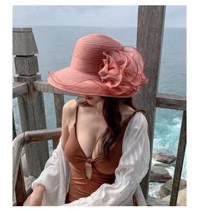 Detail of orange organza beach hat with large flower decoration and swimwear