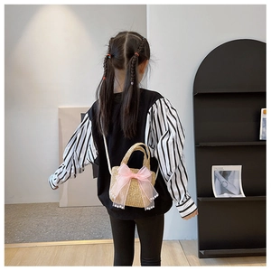 Girl wearing a pink straw woven bag with lace bow and pearl details in a modern room