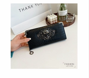 Detail of black crocodile embossed long clutch wallet with metal skull ornament