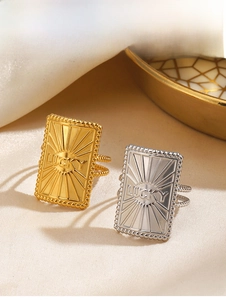 Detail of rectangular gold and silver LUCKY rings with sunburst engraving on satin
