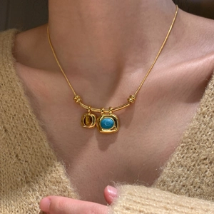 Détail du collier plaqué or 18 carats avec pendentifs en turquoise et ambre sur pull