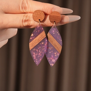Gros plan de boucles d'oreilles en bois et résine violette avec feuilles d'or