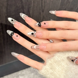 Details von Mandel-Nagel-Tips mit schwarzen Blumenmustern, Perlen und Strass-Akzenten