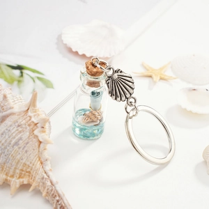 Marine style drift bottle keychain with mini shells and blue crystals on white background