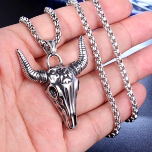 Close-up of a silver bull skull pendant with box chain held in hand for detail