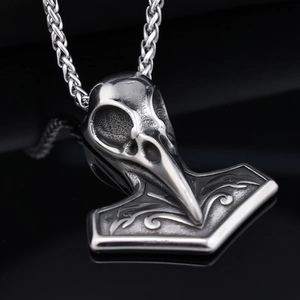 Vintage silver Viking Thor's Hammer raven skull pendant necklace on a reflective black background