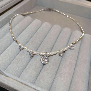 Detailed close-up of a silver bow pearl necklace with a round sparkling zircon pendant
