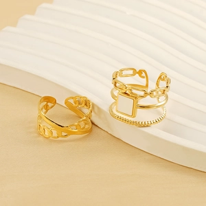 Detailed close-up of golden chain style and shell stone stackable rings on beige stand