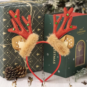 Close-up of glittery red reindeer antlers headband with plush brown base on wooden desk