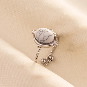 Macro detail of silver adjustable ring with oval white turquoise on beige silk fabric