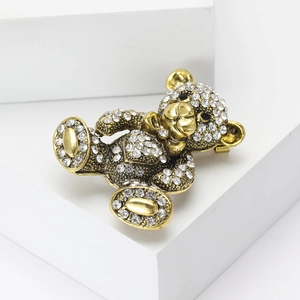 Detail of a sparkling golden teddy bear brooch adorned with clear rhinestones and black eyes