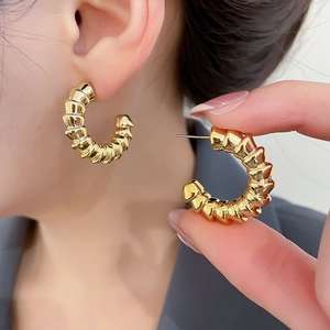 Close-up of gold-plated croissant hoop earrings featuring a textured twisted design