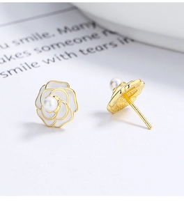 Macro shot of 925 silver camellia flower earrings with gold edges and pearl detail