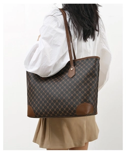 Detailed side view of large brown tote bag with geometric print on a female model