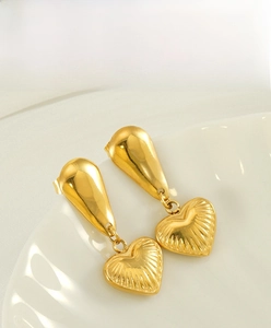 Detail of 18K gold-plated stainless steel earrings with heart charms and radial texture