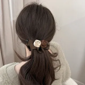 Elegant banana hair clip with satin ribbon bow and textile rose flowers in vintage style