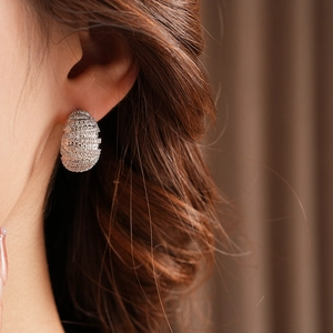Macro shot of silver zircon pavé spiral earrings on model showing detail and texture