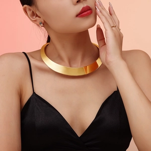 Punk style wide gold stainless steel choker necklace worn by a female model on pink background