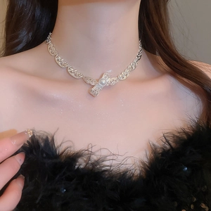 Nahaufnahme des silbernen Schleifenanhängers mit Perle an einer filigranen Metallkette