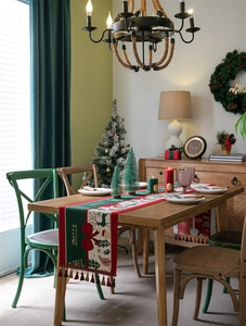 Detailed Christmas table runner with reindeer motifs and dark red tassels on festive table