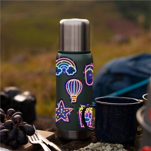 Vacuum insulated flask with holographic neon-style stickers in an outdoor camping setting