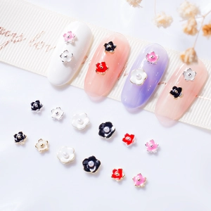 Macro detail of 3D mini 5-petal nail charms with pearl accents and enamel finish