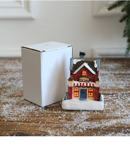 Miniature snowy Toy Land resin cottage with brick walls and white gift box on snowy wood