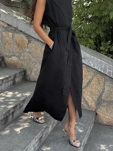 Detail of a sleeveless black linen shirt dress with a waist belt and side slit