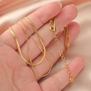 Close-up of gold double-layer snake chain necklace with heart pendant on pink satin